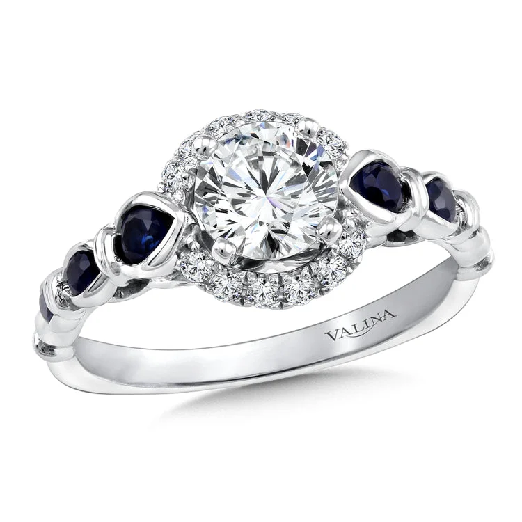 Diamond halo engagement ring mounting with blue sapphire side stones set in 14k white gold.